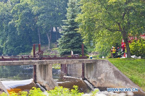 Cleanup workers vacuum oil from the water above Ceresco Dam on the Kalamazoo River in Marshall, Michigan, the United States, July 31, 2010.