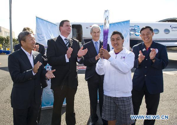 LAN SIALII (2rd R), a Maori culture performer, holds the torch during the flame arrival ceremony at the airport in Auckland, New Zealand, July 31, 2010. The torch for the Singapore 2010 Youth Olympic Games journey arrived in Auckland on Saturday.