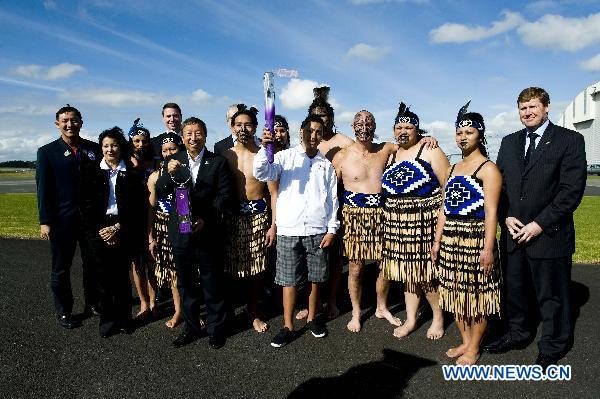 Ser Miang NG (6th L), Chairman of the Organising Committee for the Singapore 2010 Youth Olympic Games, holds the lantern as he poses for photos with guests during the flame arrival ceremony at the airport in Auckland, New Zealand, July 31, 2010.