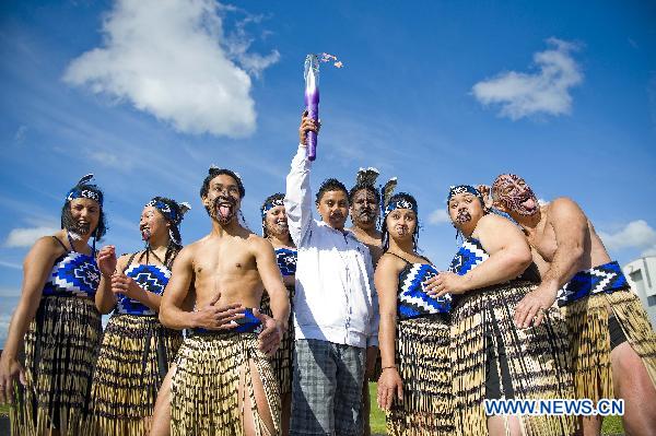 LAN SIALII (C), a Maori culture performer, holds the torch during the flame arrival ceremony at the airport in Auckland, New Zealand, July 31, 2010. The torch for the Singapore 2010 Youth Olympic Games journey arrived in Auckland on Saturday.