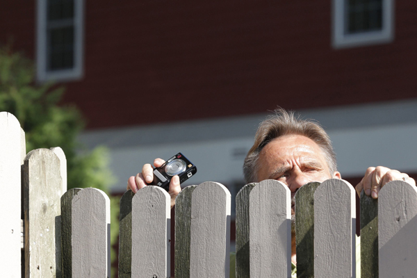 A spectator peeks over a fence as he tries to look at guests departing for Chelsea Clinton's wedding in Rhinebeck, New York July 31, 2010.