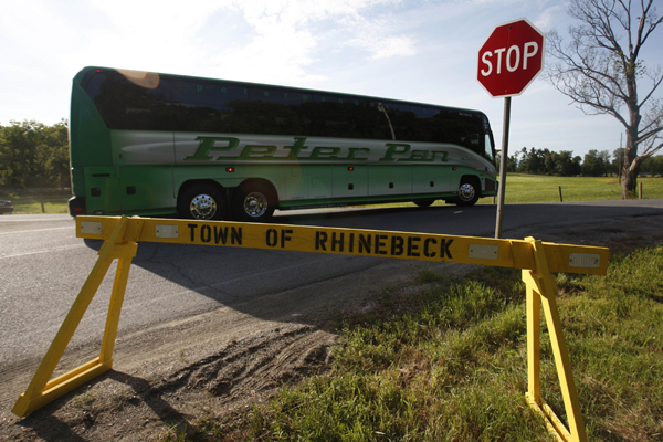 A bus full of guests drives past a police barricade on its way to the Chelsea Clinton-Marc Mezvinsky wedding in Rhinebeck, New York July 31, 2010.