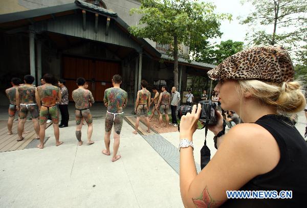 A woman watches a tattoo show during the 2010 Tattoo Exposition held in Taipei, southeast China&apos;s Taiwan, Aug. 1, 2010. The 2010 Tattoo Exposition, one of the biggest tattoo event in Asia, closed in Taipei on Sunday. [Xinhua] 