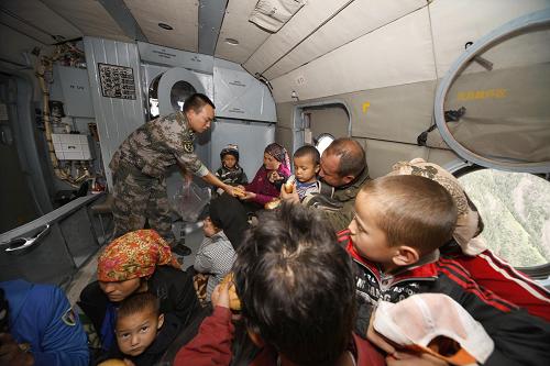 A soldier serves out food to people being rescued onto a military helicopter in Kuche County, Aksu, northwest China&apos;s Xinjiang Uygur Autonomous Region, Aug. 1, 2010.[Xinhua]