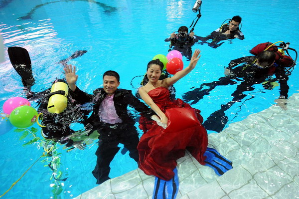 Bride Tang Mei (L3) and her husband Wu Chunpeng (L2) pose for photos during their wedding ceremony held at a swimming pool in the Natatorium of Nanjing Olympic Sports Center on China&apos;s Army Day August 1, 2010. The couple, both from the PLA army in Nanjing, held the ceremony by the pool where they first met. After a simple wedding ceremony on the 10-meter platform, they exchanged rings in the water. [Xinhua]