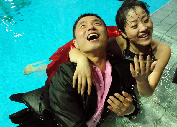 Bride Tang Mei (R) and her husband Wu Chunpeng pose for photos after exchanging rings in a swimming pool at the Natatorium of Nanjing Olympic Sports Center August 1, 2010. [Xinhua] 