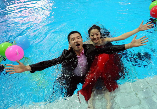 Bride Tang Mei (R) and her husband Wu Chunpeng pose for photos during their wedding ceremony held in a swimming pool at the Natatorium of Nanjing Olympic Sports Center, August 1, 2010. [Xinhua]