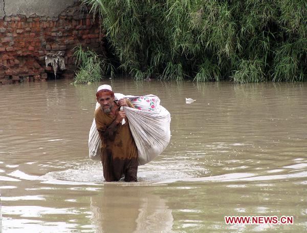 A Pakistani man walks through the waterlogged street in northwest Pakistan&apos;s Nasir-Bagh on Aug. 1, 2010. The current horrible wave of floods and landslides triggered by torrential monsoon rains has killed more than 900 people in Pakistan while 1 million people have become homeless as the flood is now hitting western and southern parts of the country. [Saeed Ahmad/Xinhua]