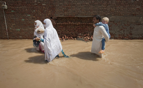 A family wades through receding flood waters while returning to their homes in Nowshera, located in Pakistan&apos;s northwest Khyber-Pakhtunkhwa Province August 1, 2010. [Xinhua]