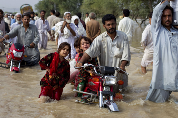 A man evacuates his children through waist-deep waters after heavy flooding in Nowshera, located in Pakistan&apos;s northwest Khyber-Pakhtunkhwa Province August 1, 2010. [Xinhua]