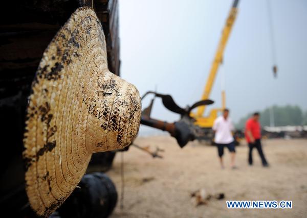 An oil-dotted strawhat is seen in Dalian, northeast China&apos;s Liaoning Province, July 31, 2010. Local fishermen joined the team to clean the oil spill at beaches, tourist attractions, marine parks and so on after the oil pipe explosion at Dalian Xingang Harbor. [Xinhua]