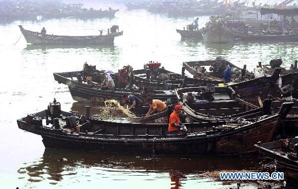 Fishermen clean their boats in Dalian, northeast China&apos;s Liaoning Province, July 29, 2010. Local fishermen joined the team to clean the oil spill at beaches, tourist attractions, marine parks and so on after the oil pipe explosion at Dalian Xingang Harbor. [Xinhua]