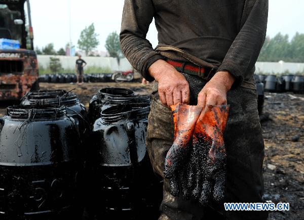 A fisherman takes off his gloves in Dalian, northeast China&apos;s Liaoning Province, July 29, 2010. Local fishermen joined the team to clean the oil spill at beaches, tourist attractions, marine parks and so on after the oil pipe explosion at Dalian Xingang Harbor. [Xinhua]