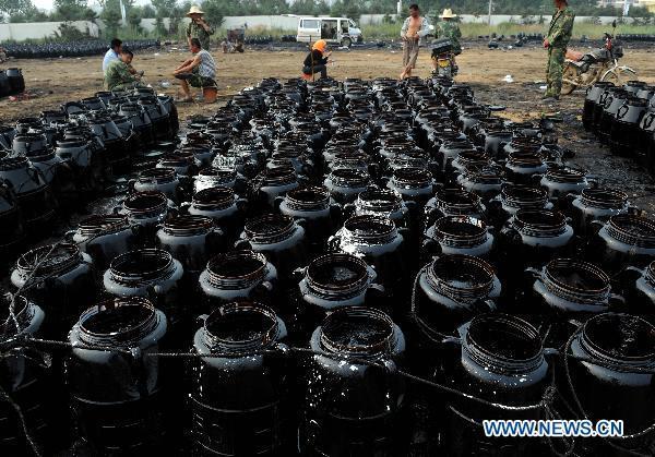 Barrels filled with recovered oil are seen in Dalian, northeast China&apos;s Liaoning Province, July 29, 2010. Local fishermen joined the team to clean the oil spill at beaches, tourist attractions, marine parks and so on after the oil pipe explosion at Dalian Xingang Harbor. [Xinhua]
