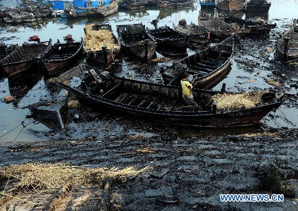 Fishing boats are covered by oil after the cleaning work in Dalian, northeast China&apos;s Liaoning Province, July 29, 2010. Local fishermen joined the team to clean the oil spill at beaches, tourist attractions, marine parks and so on after the oil pipe explosion at Dalian Xingang Harbor. [Xinhua]