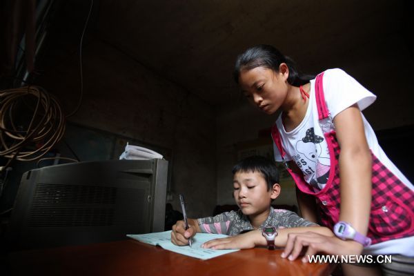 Photo taken on July 29, 2010 shows 13-year-old Xiao Fen (R) tutors her brother, ten-year-old Xiao Han in Shaoyang County, central China&apos;s Hunan Province. [Xinhua]