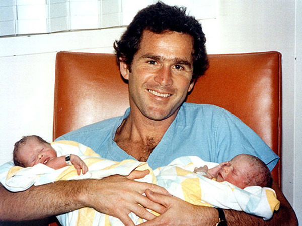 Former U.S. President George W. Bush holds his twin daughters Barbara and Jenna in arms [gb.cri.cn]