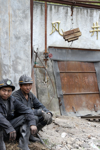 Two miners sit nearby the air shaft waiting for the news about their trapped colleagues after a gas outburst at the Mingyang Coal Mine in Changgang township, Renhuai city, Southwest China&apos;s Guizhou province, August 3, 2010. [Xinhua]