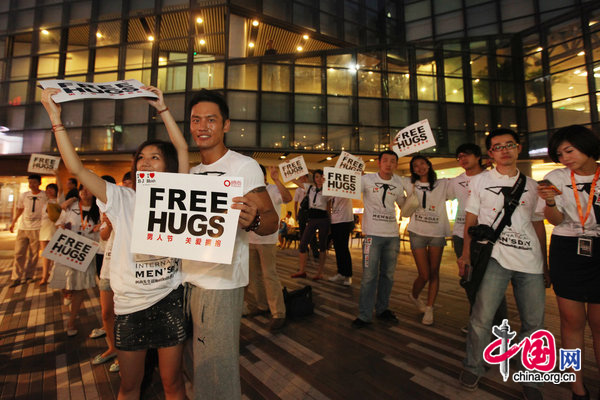 People ccelebrate International Men&apos;s Day (IMD) at Sanlitun Village in Beijing, August 3, 2010. Several men hold a slogan of &apos;Free Hugs&apos; to ask strangers for a hug during a &apos;Free Hug&apos; event. [CFP]