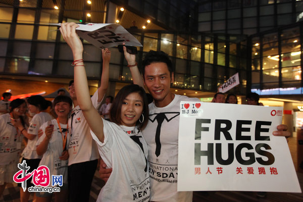 People ccelebrate International Men&apos;s Day (IMD) at Sanlitun Village in Beijing, August 3, 2010. Several men hold a slogan of &apos;Free Hugs&apos; to ask strangers for a hug during a &apos;Free Hug&apos; event. [CFP]