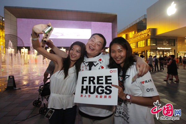 People ccelebrate International Men&apos;s Day (IMD) at Sanlitun Village in Beijing, August 3, 2010. Several men hold a slogan of &apos;Free Hugs&apos; to ask strangers for a hug during a &apos;Free Hug&apos; event. [CFP]