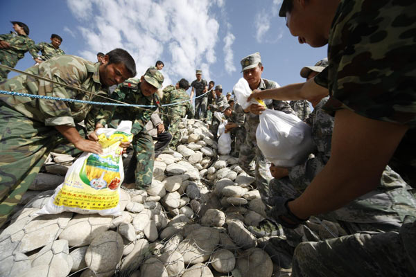 Paramilitary policemen pass sandbags used to strengthen a dyke in Hotan county of Northwest China&apos;s Xinjiang Uygur autonomous region, August 3, 2010. [Xinhua]