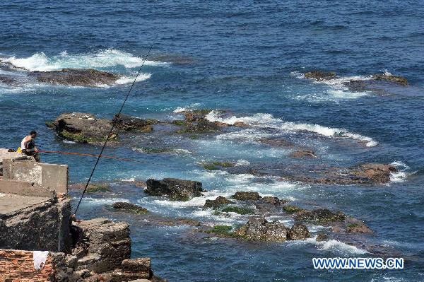 People fish during the summer vacation at the rocky coast and beach near Algiers, Algeria, Aug. 3, 2010. (Xinhua/Kadri Mohamed) 