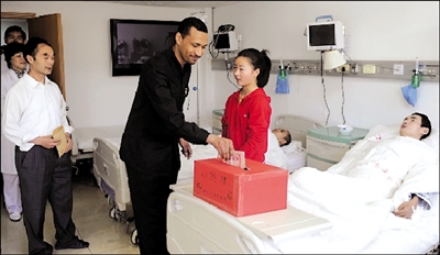 Huang Feng (center) thanks a Sudanese man, who donated 10,000 yuan ($1,476) for her father Huang Zhiren's treatment, in a ward of the General Hospital of Armed Police Forces in Beijing on May 19. 