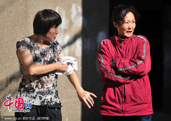 Luo Chun&apos;e (in red) chats with a neighbor under the sun near her house in Wuhan, Central China&apos;s Hubei province, August 4, 2010. [CFP]