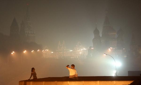 A couple visit the Red Square among thick smog in Moscow, capital of Russia, Aug. 4, 2010. Moscow suffered serious air pollution due to the forest and peat fires. [Lu Jinbo/Xinhua]