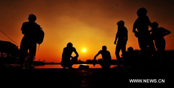 Silhouettes of swimmers waiting near the Xiangjiang River are seen in Changsha, capital of central China&apos;s Hunan Province, Aug. 4, 2010. The highest temperature of Changsha reached 40 degrees Centigrade Wednesday. [Xinhua]