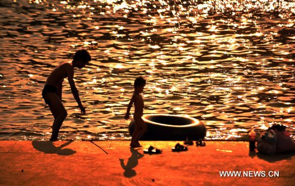 Silhouettes of swimmers waiting near the Xiangjiang River are seen in Changsha, capital of central China&apos;s Hunan Province, Aug. 4, 2010. The highest temperature of Changsha reached 40 degrees Centigrade Wednesday. [Xinhua]