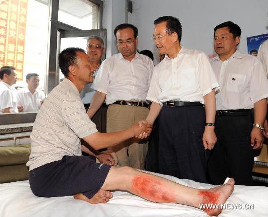 Chinese Premier Wen Jiabao (2nd R), shakes hands with an injured man in the flood-hit area in Yongji County of Jilin City, northeast China's Jilin Province on Aug. 3, 2010. [Xinhua]