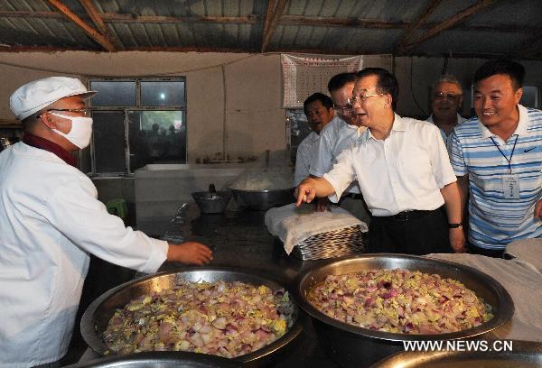 Chinese Premier Wen Jiabao (3rd R), talks with a chef preparing food for flood-affected residents in the flood-hit area in Yongji County of Jilin City, northeast China's Jilin Province on Aug. 3, 2010. [Xinhua]