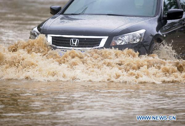 A car moves on flood-ravaged street in Jilin City, northeast China&apos;s Jilin Province, Aug. 5, 2010. [Xinhua] 