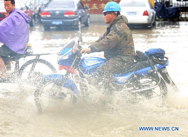 People ride a moto cycles on flood-ravaged street in Jilin City, northeast China&apos;s Jilin Province, Aug. 5, 2010. [Xinhua]