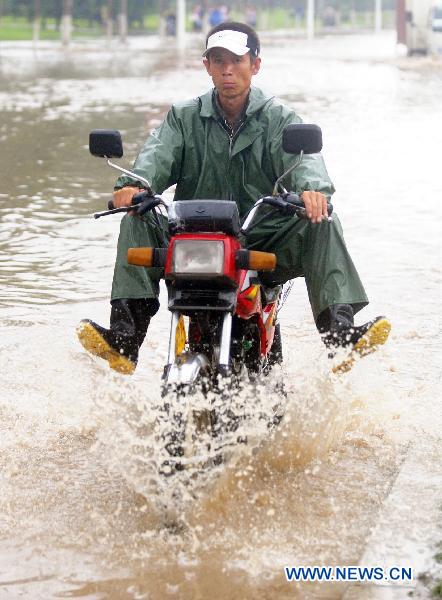 A man rides a moto cycle on flood-ravaged street in Jilin City, northeast China&apos;s Jilin Province, Aug. 5, 2010. [Xinhua]