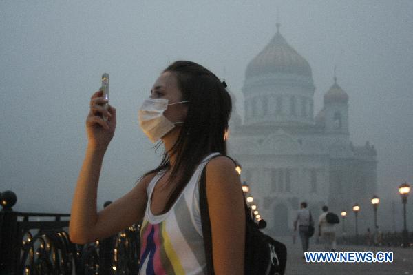 A woman is taking photo in the street of Moscow on Aug 4, when the whole city was filled with the smoke.[Xinhua]