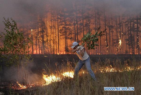 Two man are fighting with rampant wildfires in the central Russia, on Aug 4..[Xinhua]