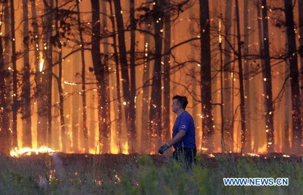 A firefighter is fighting with rampant wildfires in the central Russia, on Aug 4. [Xinhua]