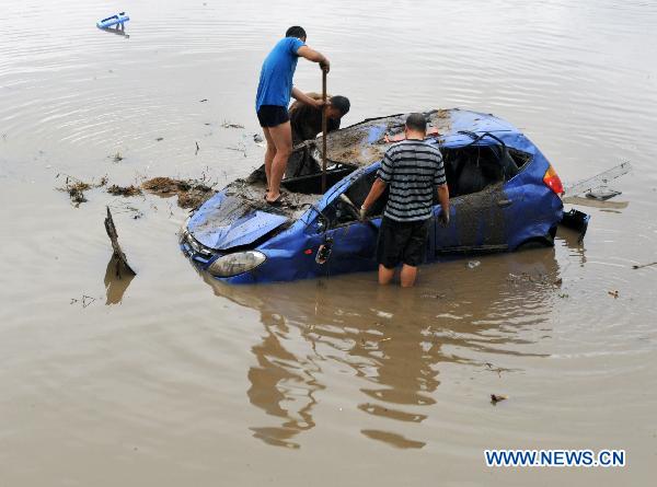 Local residents try to retrieve a car at a flood-ravaged street in Yongji County, northeast China's Jilin Province, Aug. 5, 2010. Rainfall reached 204 mm over the previous 24 hours as of 8 a.m. Thursday in central Jilin, the provincial meteorological station said. Constant rains had forced seven of the 25 medium and large reservoirs in Jilin City, including Fengman, Baishan and Xingxingshao, to discharge water, and their levels were falling, according to Jilin municipal government. [Xinhua]