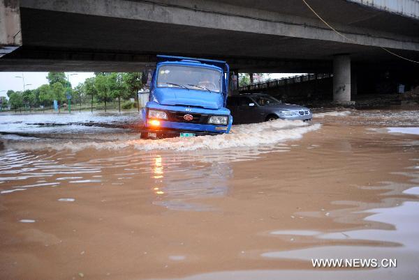 Vehicles move in a flooded street in Xinyu, east China&apos;s Jiangxi Province on Aug. 5, 2010, after heavy rainstorms. [Xinhua] 