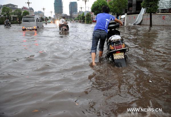 Residents make their way forward in a flooded street in Xinyu, east China&apos;s Jiangxi Province on Aug. 5, 2010, after heavy rainstorms. [Xinhua] 