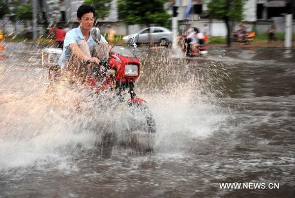 A resident rides a motorbike in a flooded street in Xinyu, east China&apos;s Jiangxi Province on Aug. 5, 2010, after heavy rainstorms.. [Xinhua] 