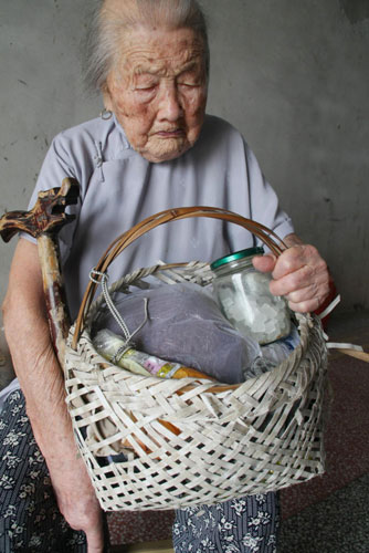 102-year-old Chu Xiangfeng holds her walking stick and a basket in Xichang town of Hai'an county, Jiangsu province, August 4, 2010. 
