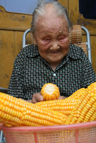 102-year-old Cui Bozhen shucks corn in Xichang town of Hai'an county, Jiangsu province, August 4, 2010.