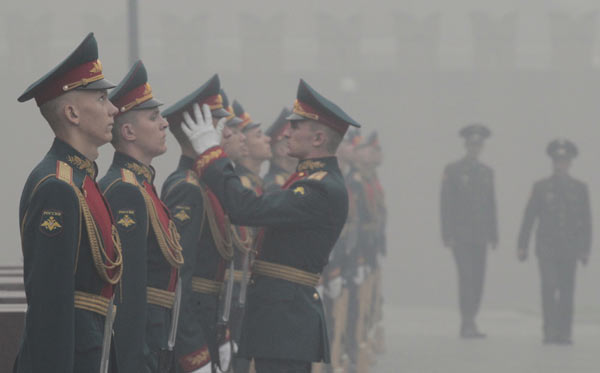 A guard of honour adjusts the service caps of his associates before a wreath-laying ceremony at the Tomb of the Unknown Soldier by the Kremlin wall as a heavy smog shrouded the capital in Moscow, August 6, 2010. [Xinhua] 