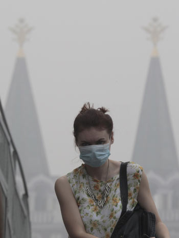 A woman wears a mask to protect herself from the smell of heavy smog, caused by peat fires in nearby forests, as she walks in central Moscow, August 6, 2010. [Xinhua] 