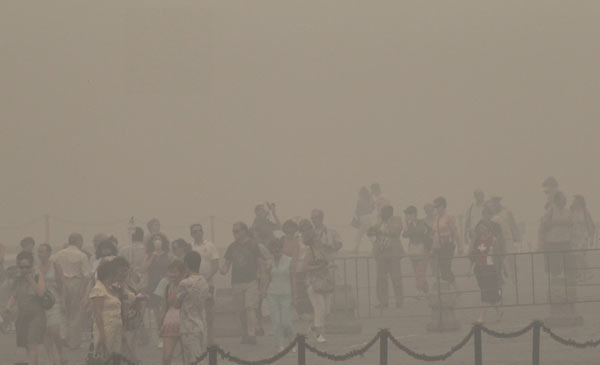 Tourists walk along Red Square amidst heavy smog, caused by peat fires in nearby forests, in central Moscow, August 6, 2010. [Xinhua]