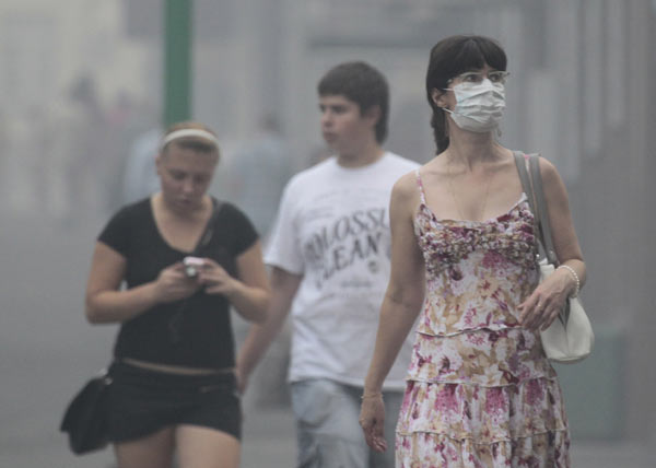 A woman wears a mask to protect herself from the smell of heavy smog, caused by peat fires in nearby forests, as she walks in central Moscow, August 6, 2010. [Xinhua]